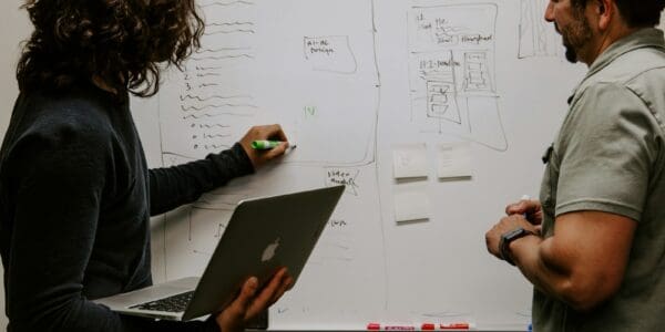 man wearing gray polo shirt beside dry-erase board