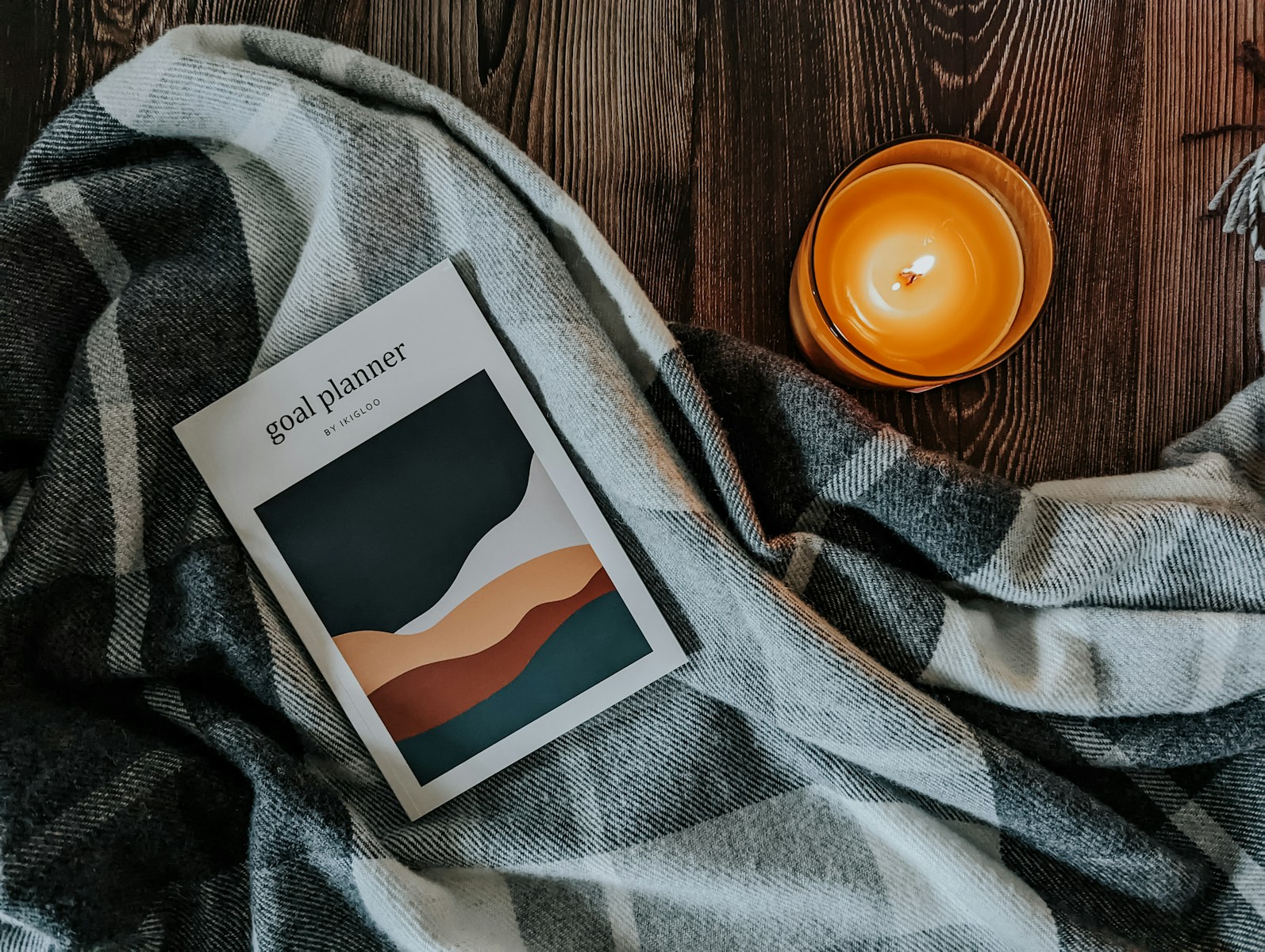 a book sitting on top of a blanket next to a candle